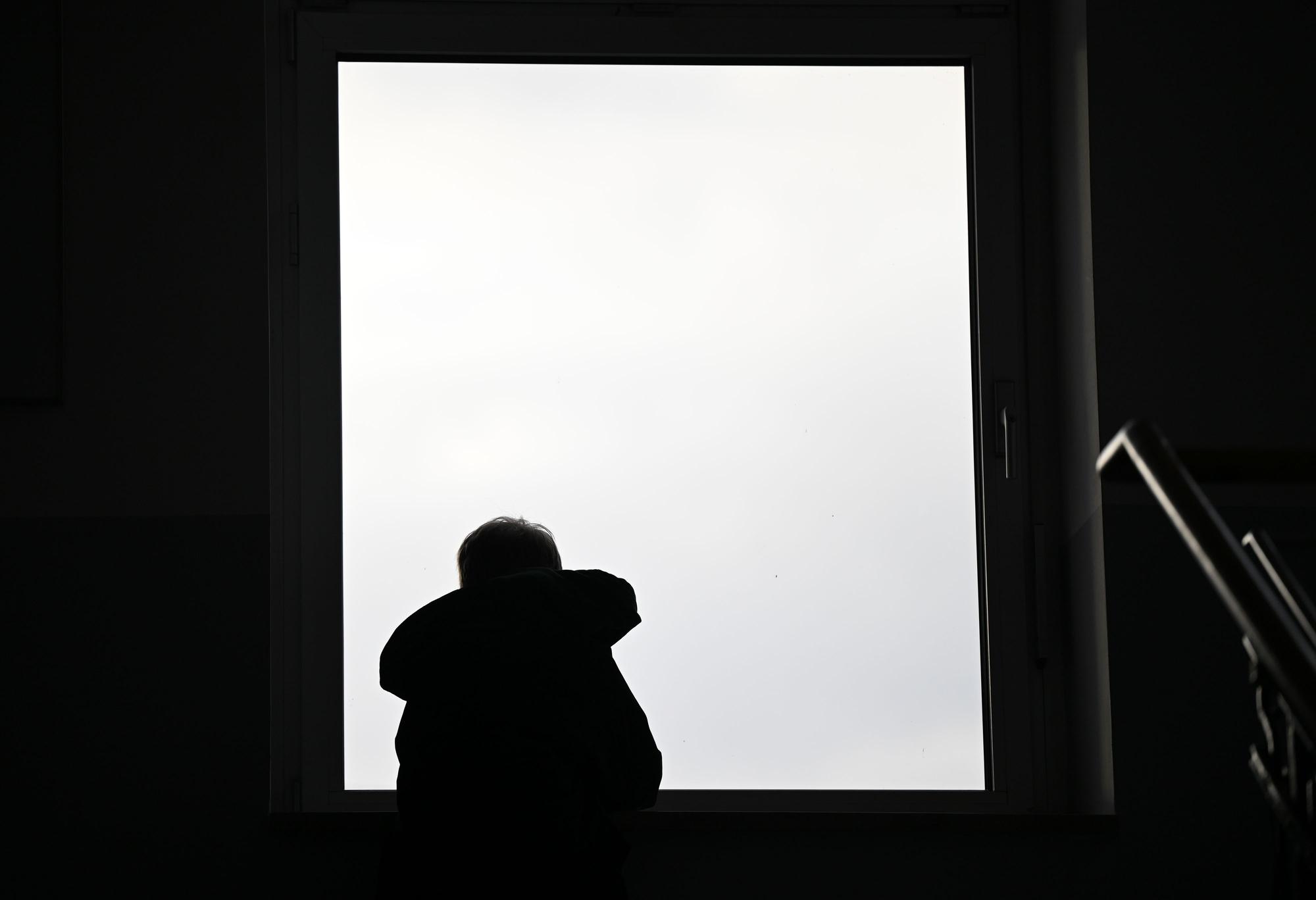Ein Junge sitzt in einem Treppenhaus an einem Fenster. (Symbolbild)
