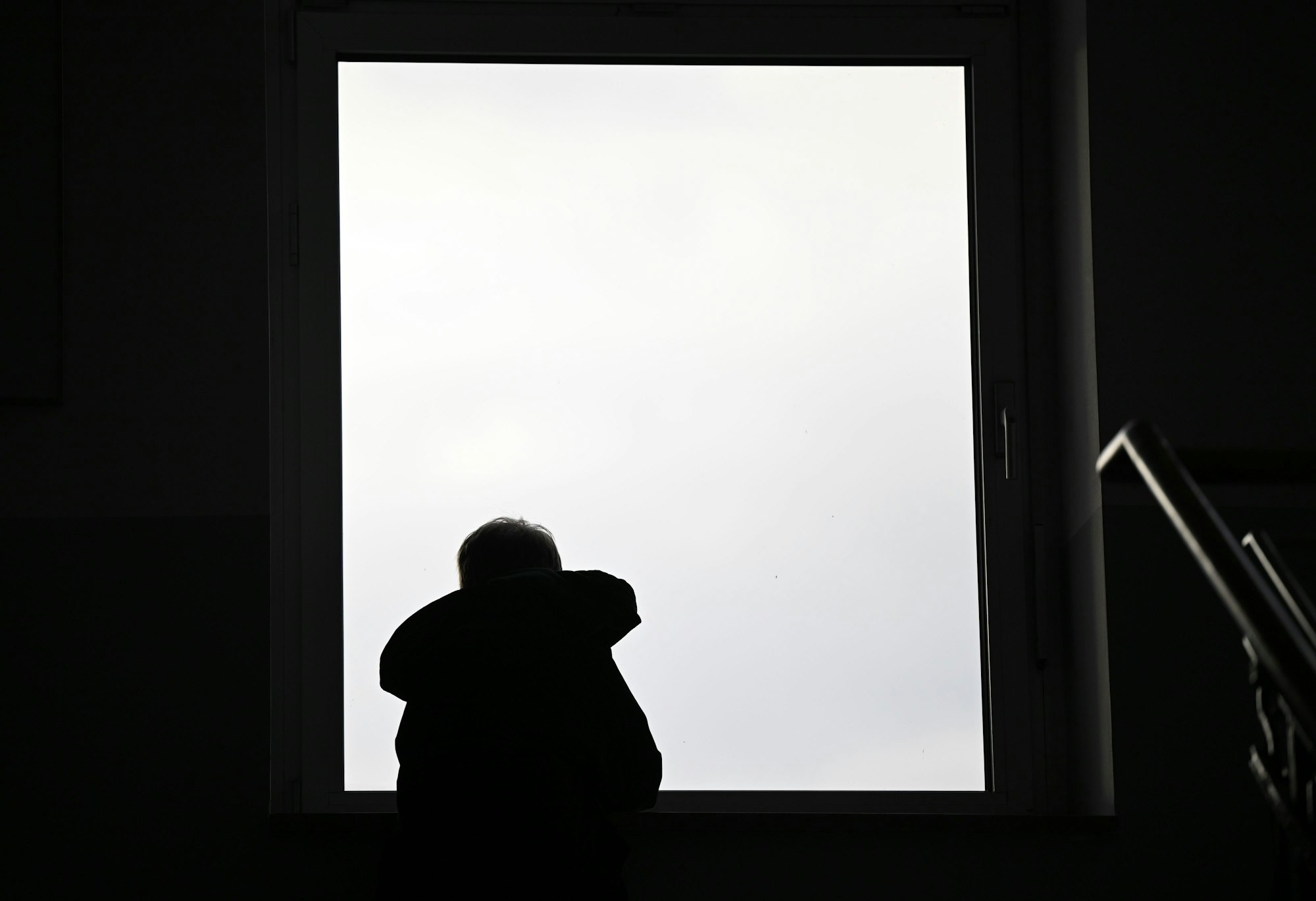 Ein Junge sitzt in einem Treppenhaus an einem Fenster. (Symbolbild)