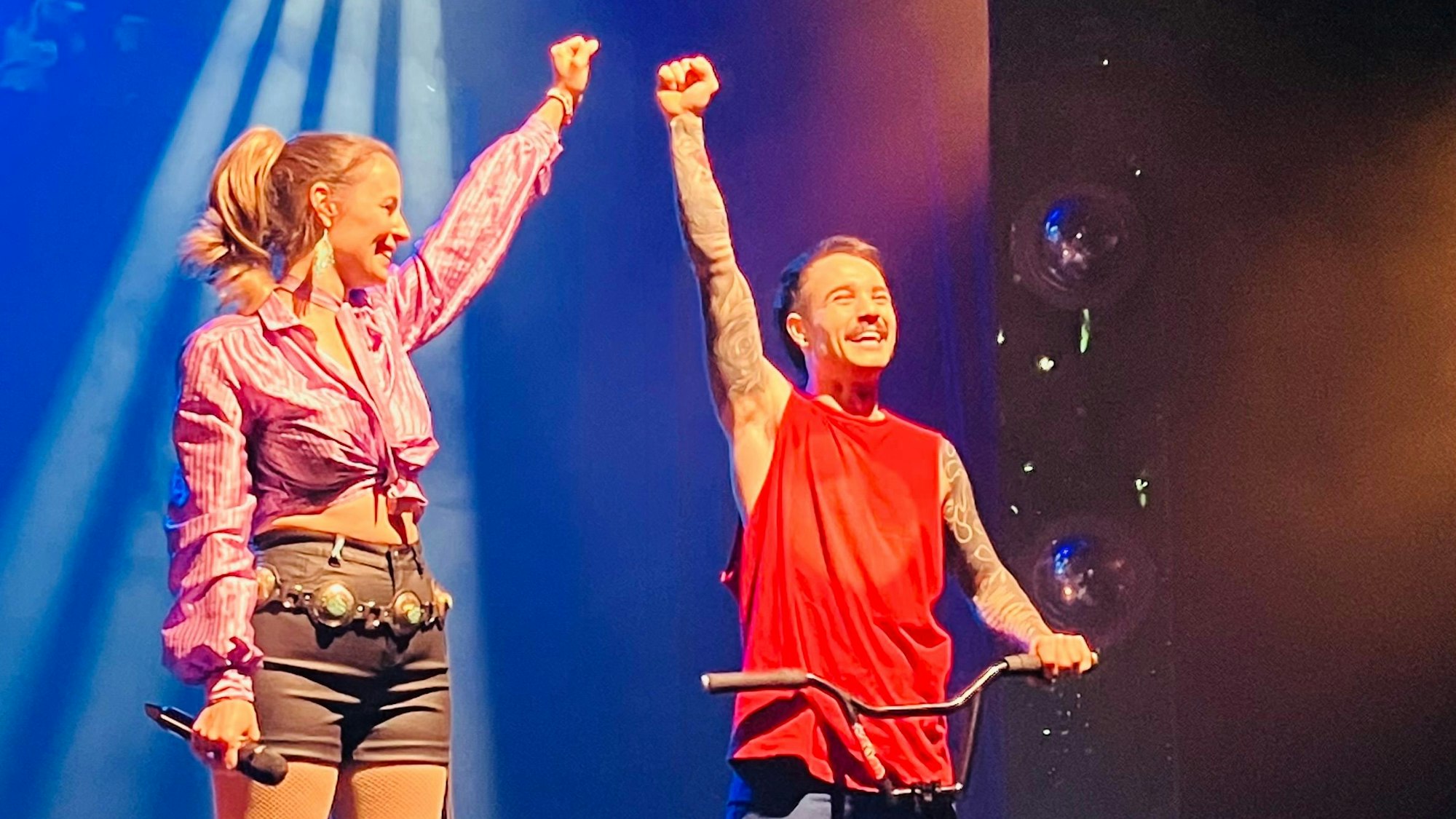 Sängerin Maja Matic und BMX-Artist Inigo Arroyo heben die Arme.