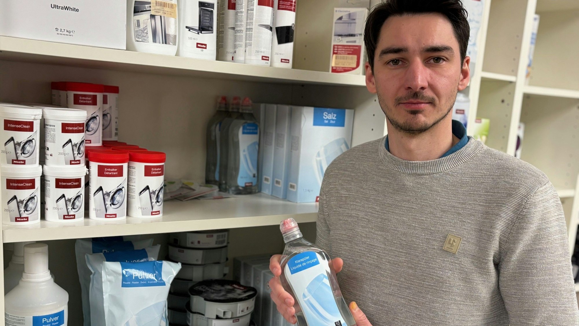 Auf dem Bild ist ein Mann mit einer Flasche Pflegemittel in der Hand zu sehen.