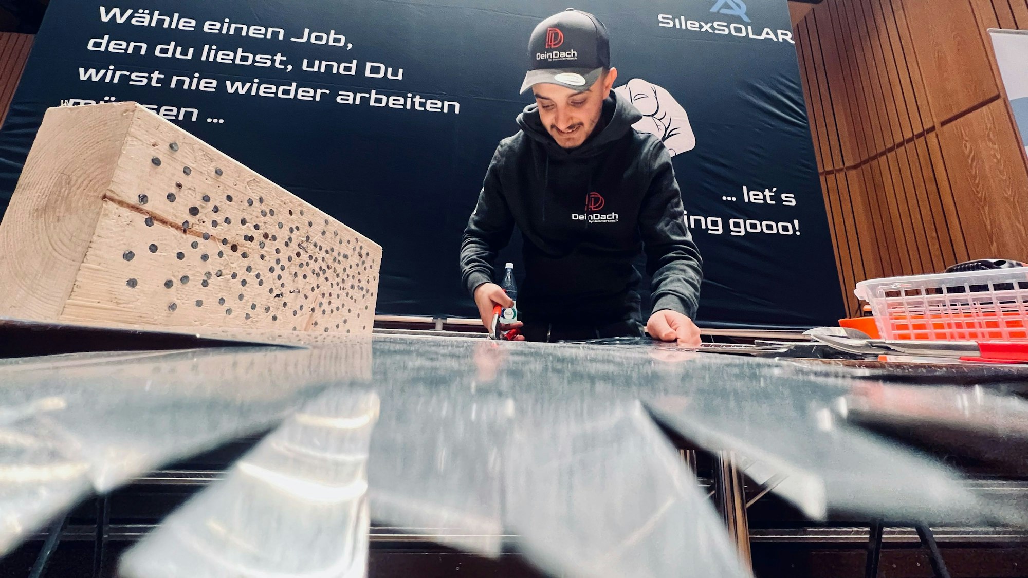 Ein junger Mann zeigt und erklärt, was zum Beruf des Dachdeckers dazu gehört.