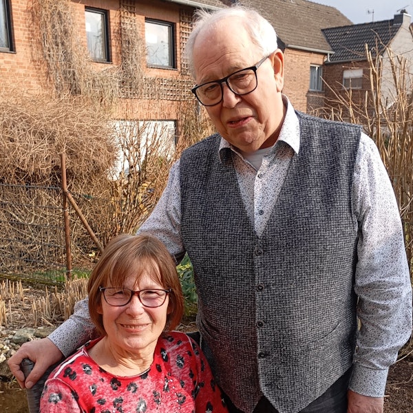 Ein Mann steht neben einer Frau, die sitzt.