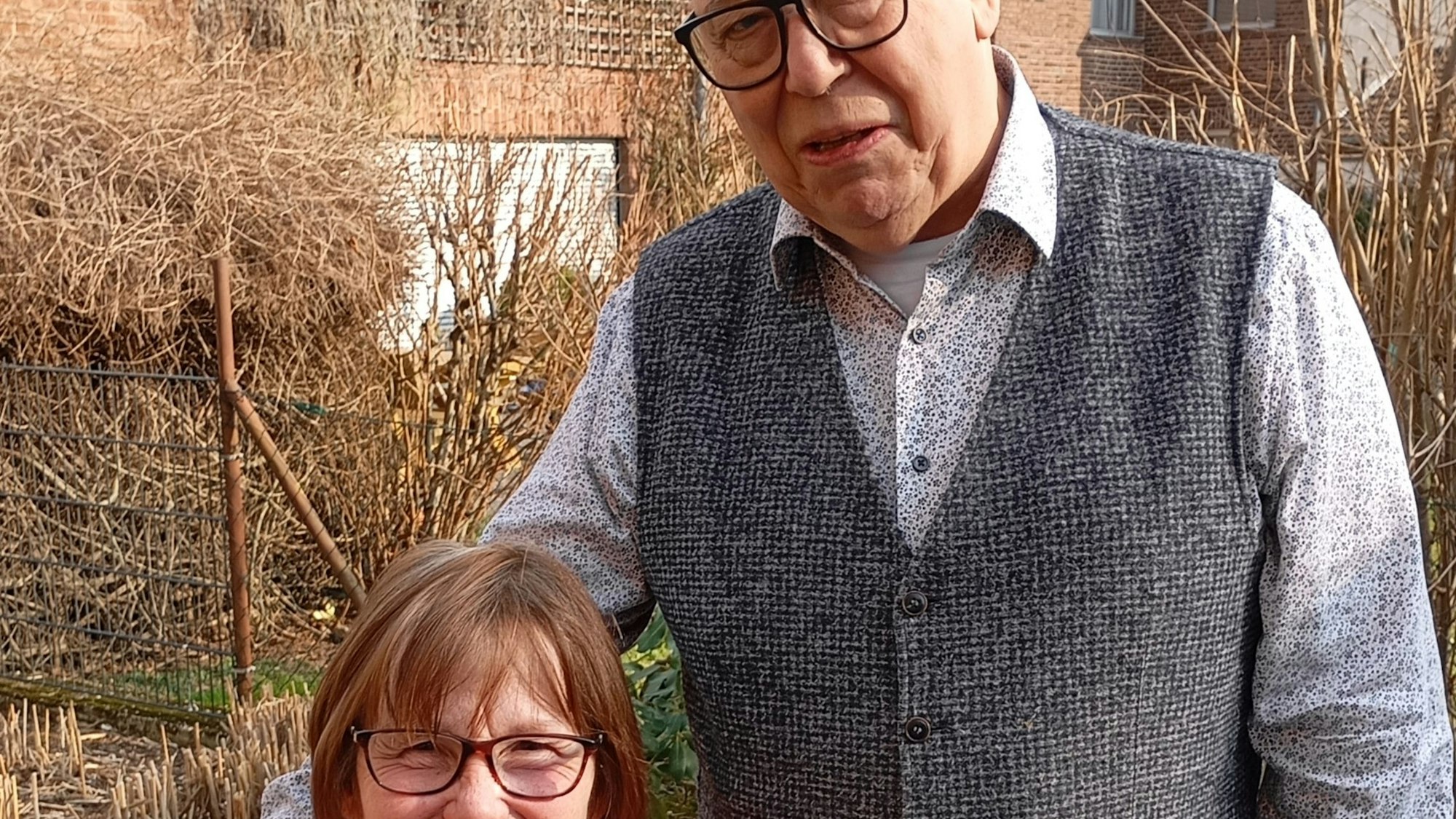 Ein Mann steht neben einer Frau, die sitzt.