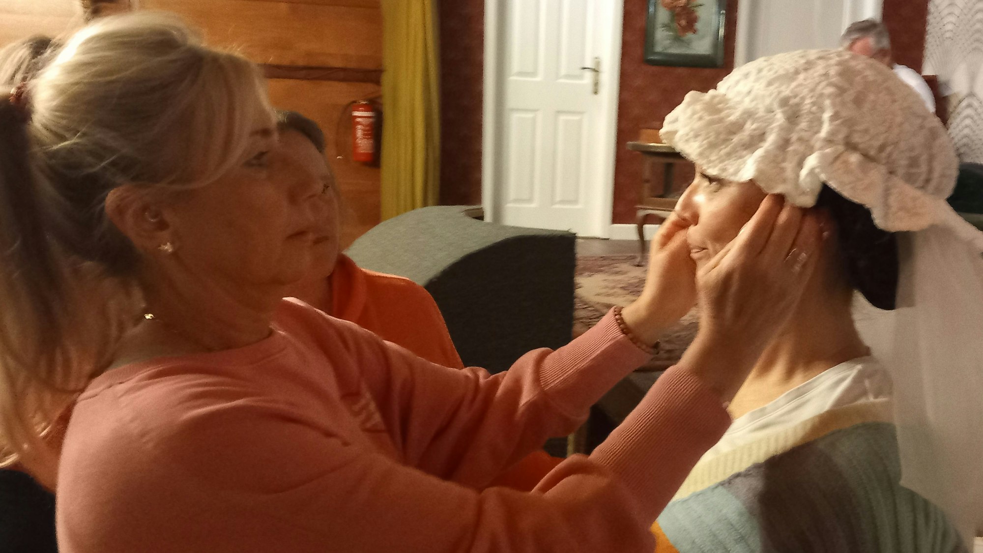 Melanie Jäger passt die Kopfbedeckung von Michaela Zadeck an.