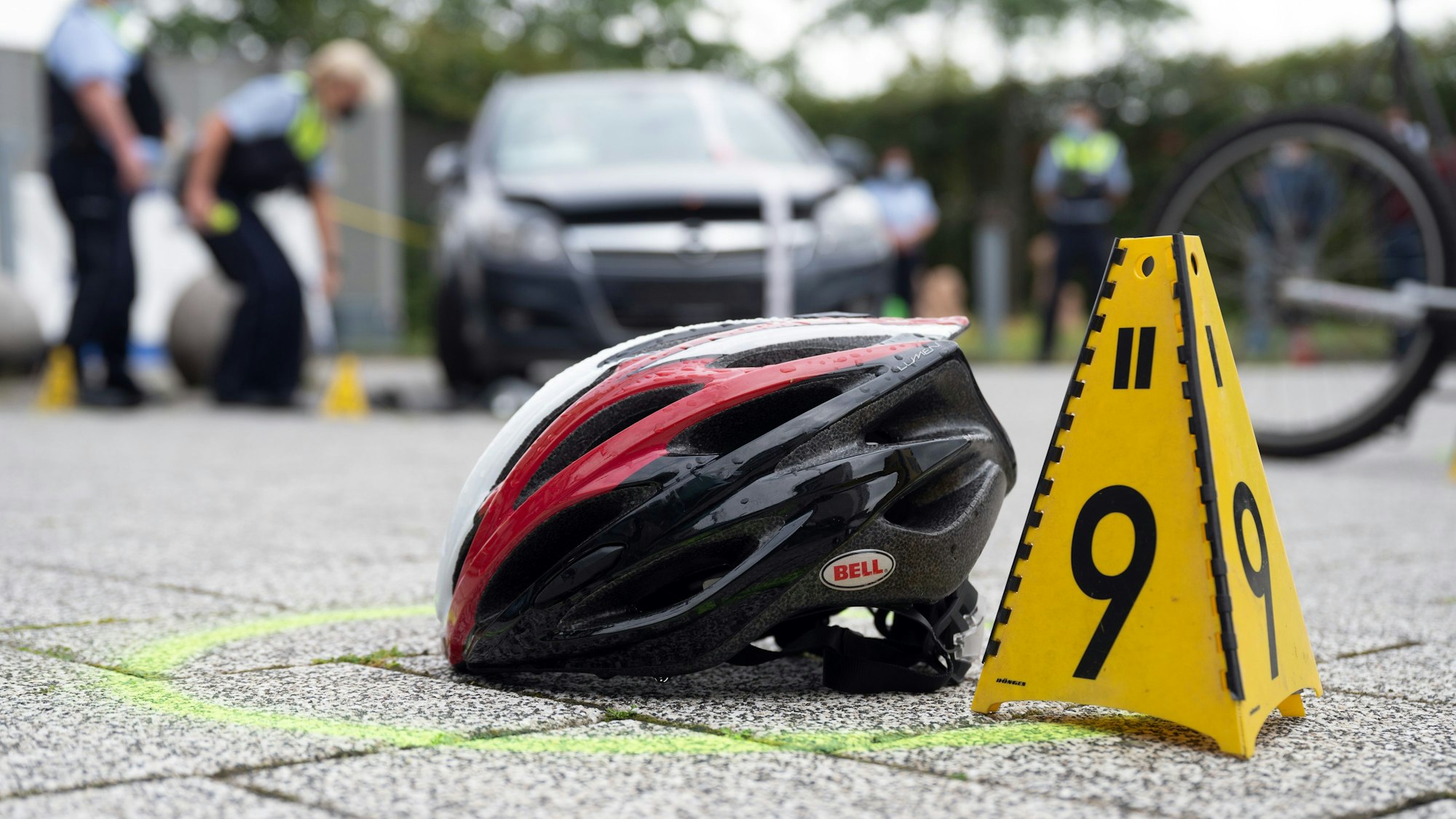 Ein Fahrradhelm liegt bei einer Verkehrsunfallaufnahme auf dem Boden.
