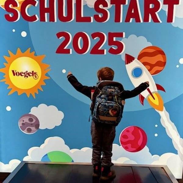 Der neue Ranzen wird vor der Fotowand demonstriert