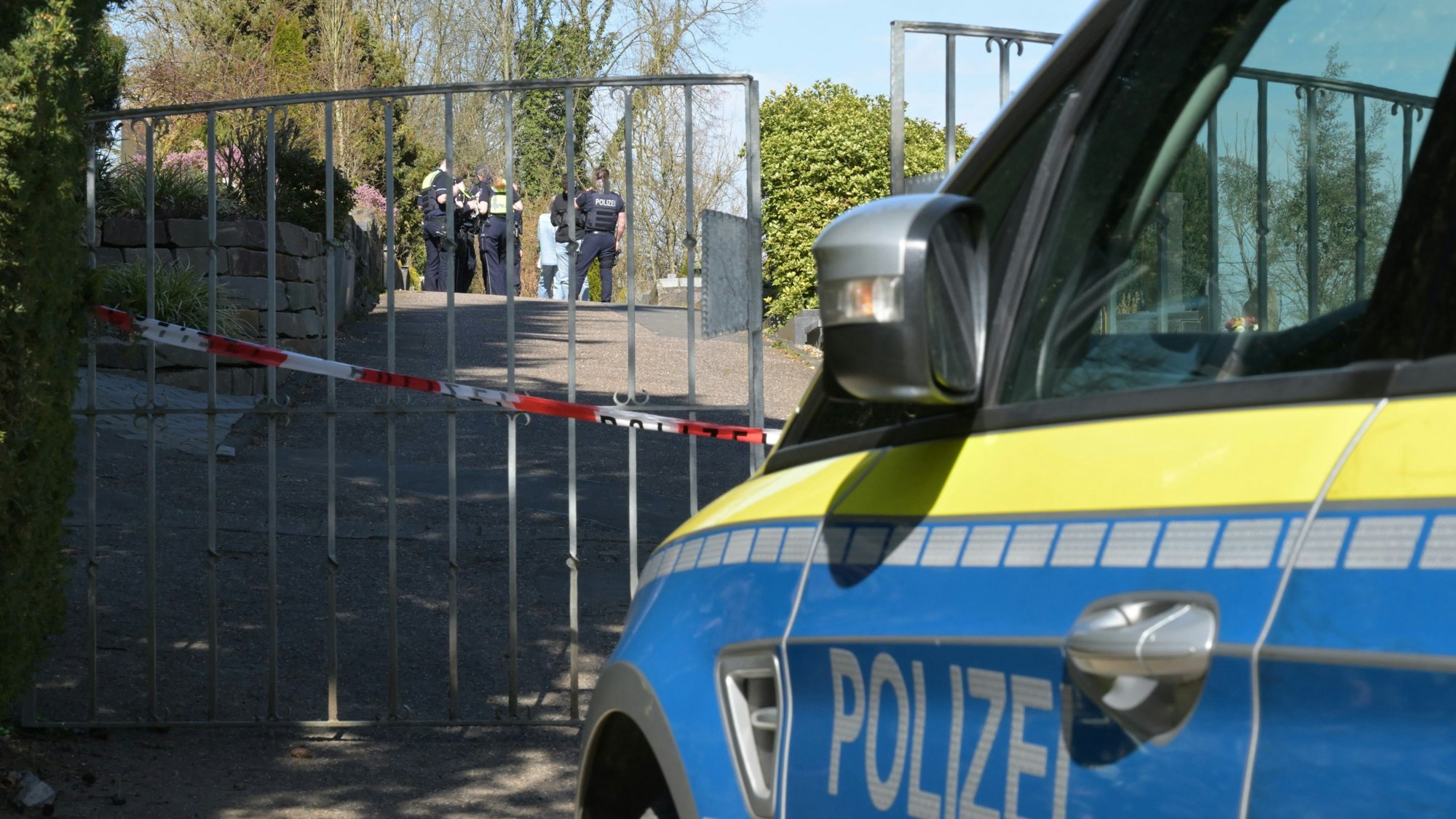 Ein Polizeiwagen steht vor dem Tor des Volbergerer Friedhofs, Flatterband versperrt den Zugang.