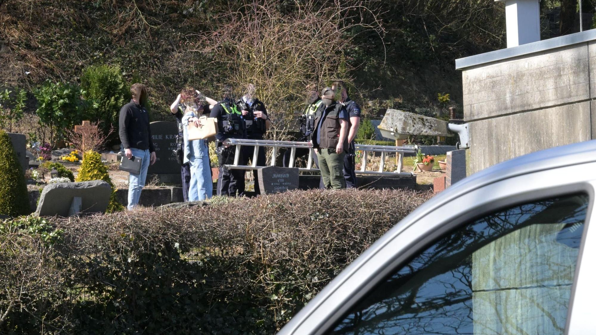 Ermittler der Polizei stehen mit einer Leiter auf dem Volberger Friedhof in Rösrath-Hoffnungtshal.