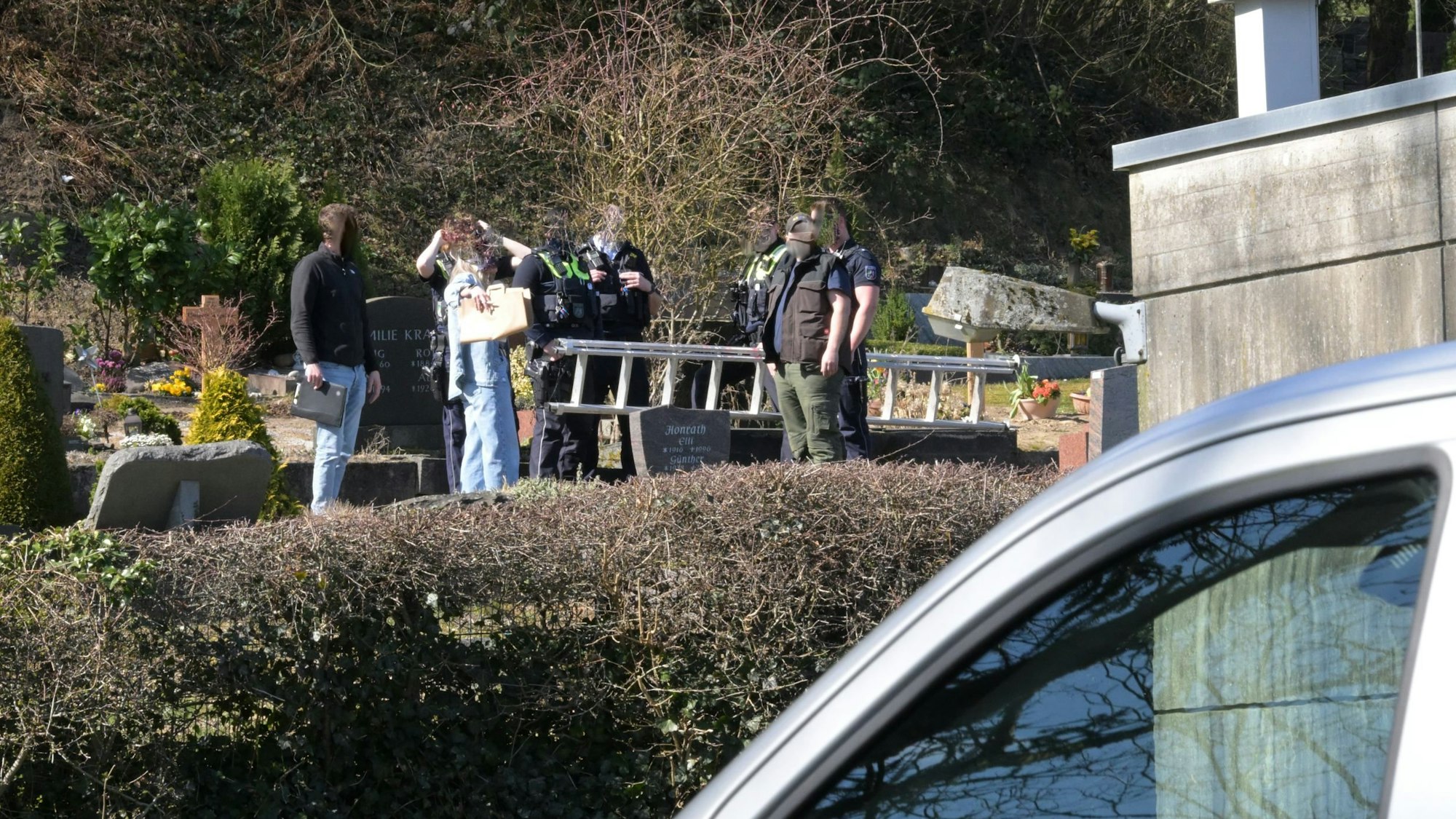 Ermittler der Polizei stehen mit einer Leiter auf dem Volberger Friedhof in Rösrath-Hoffnungtshal.