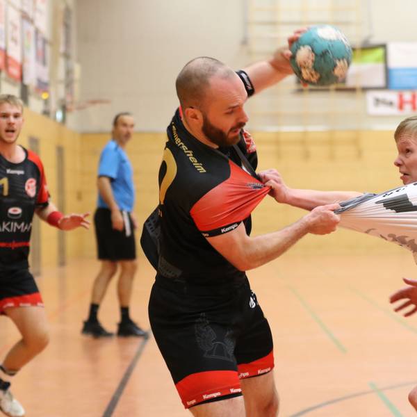 Simon Schöller hält mit der linken Hand den Ball in die Höhe und greift mit der rechten nach dem Trikot seines Gegenspielers, der ihn am Schlafittchen gepackt hat.
