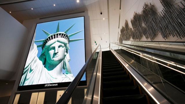 ARCHIV - 10.06.2020, USA, New York: Ein elektronisches Bildschirmbild der Freiheitsstatue begrüßt ankommende Reisende auf einer Rolltreppe im neuen Terminal B des Flughafens LaGuardia. (zu dpa: «Reisehinweise für USA jetzt mit Info zu Abschiebehaft») Foto: Mark Lennihan/AP/dpa +++ dpa-Bildfunk +++