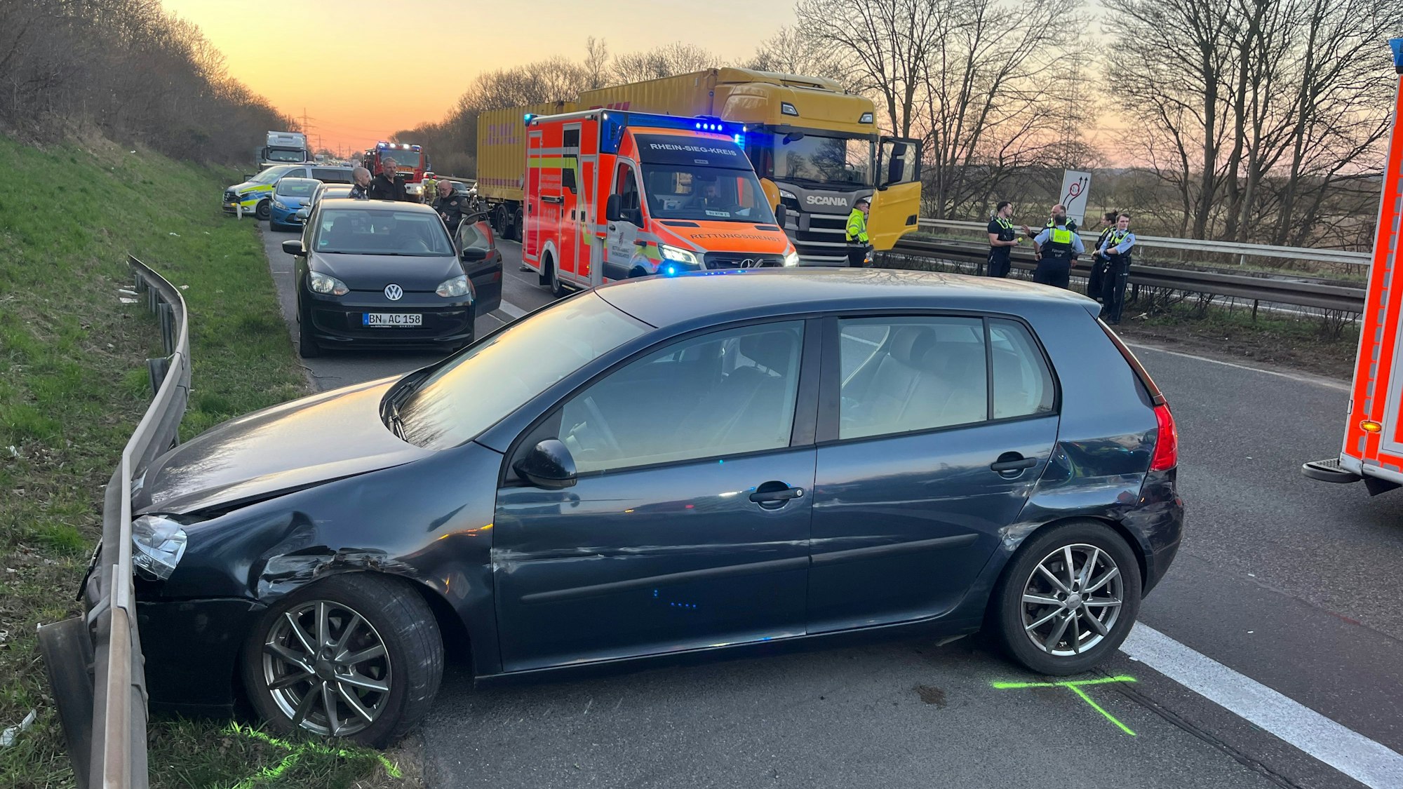 Ein beschädigtes Auto steht an der Seitenschutzplanke, dahinter ein Rettungswagen und ein Lastwagen.
