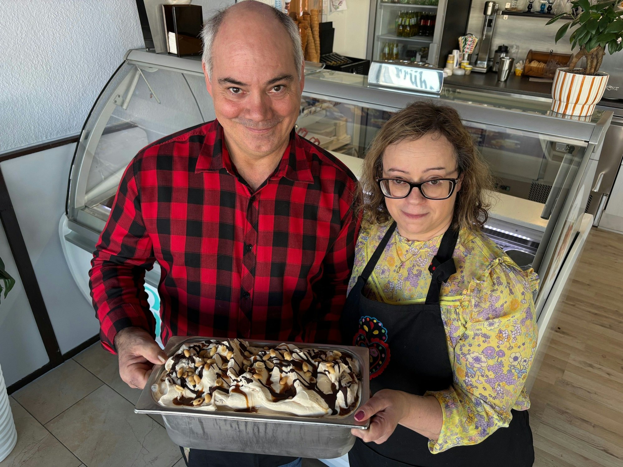 Auf dem Bild ist ein Ehepaar zu sehen, dass eine große Schüssel selbst gemachtes Eis in die Kamera hält.