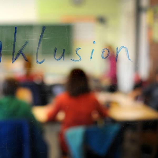 Schüler sitzen am in einer Inklusions-Klasse unter dem Schriftzug „Inklusion“