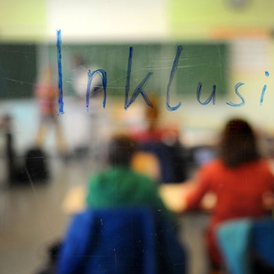 Schüler sitzen am in einer Inklusions-Klasse unter dem Schriftzug „Inklusion“