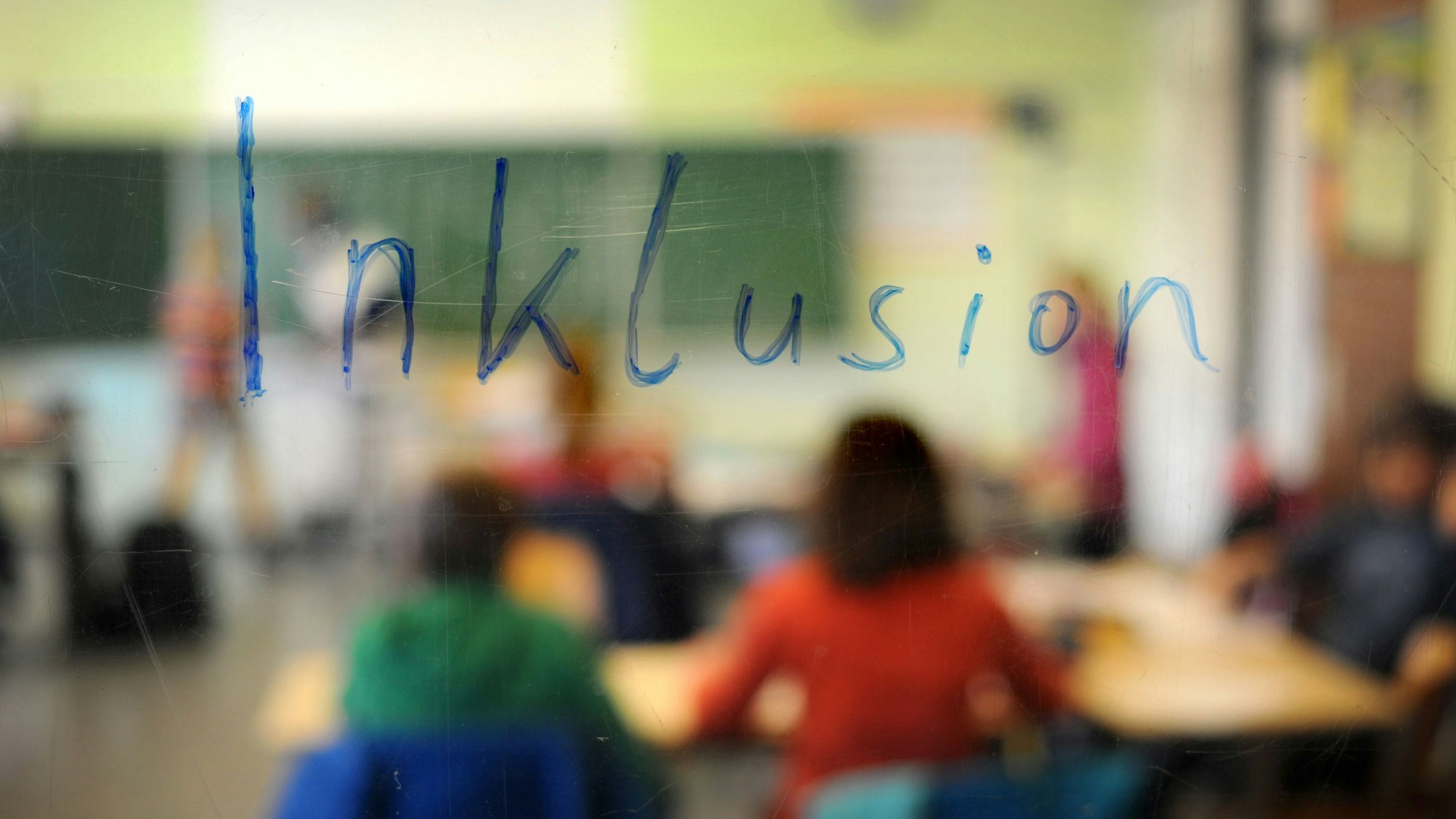 Schüler sitzen am in einer Inklusions-Klasse unter dem Schriftzug „Inklusion“
