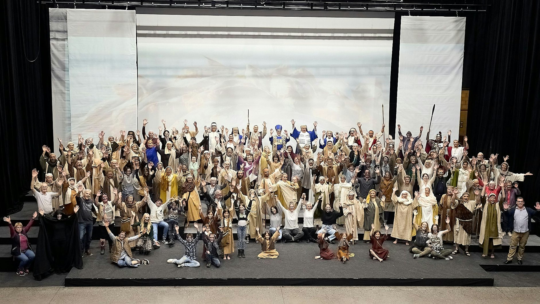 Die Darsteller haben sich in ihren Kostümen zum Gruppenbild auf der Bühne versammelt.