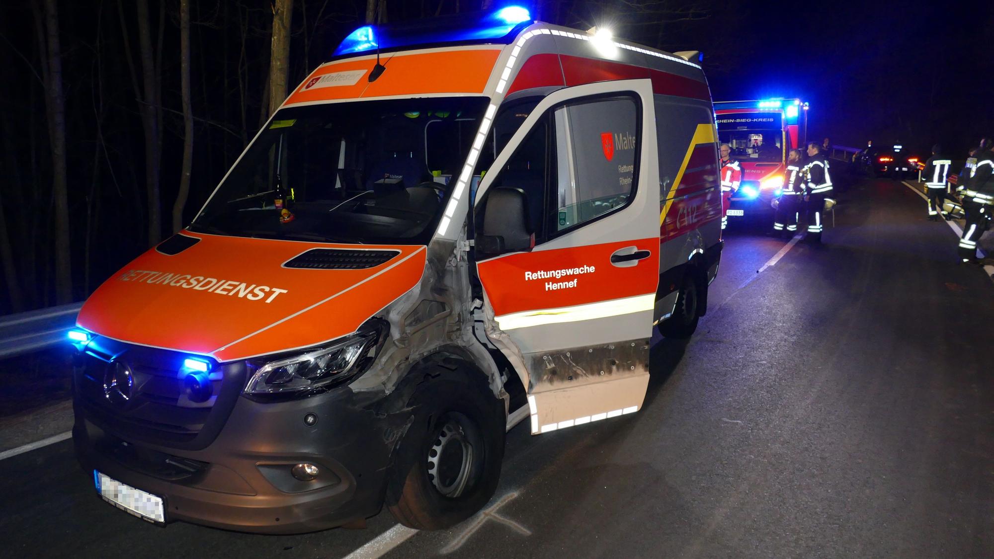 Ein defekter Krankenwagen steht in der Nacht auf einer Straße. Die eine Seite ist nach einem Unfall verbeult, die Tür steht offen.