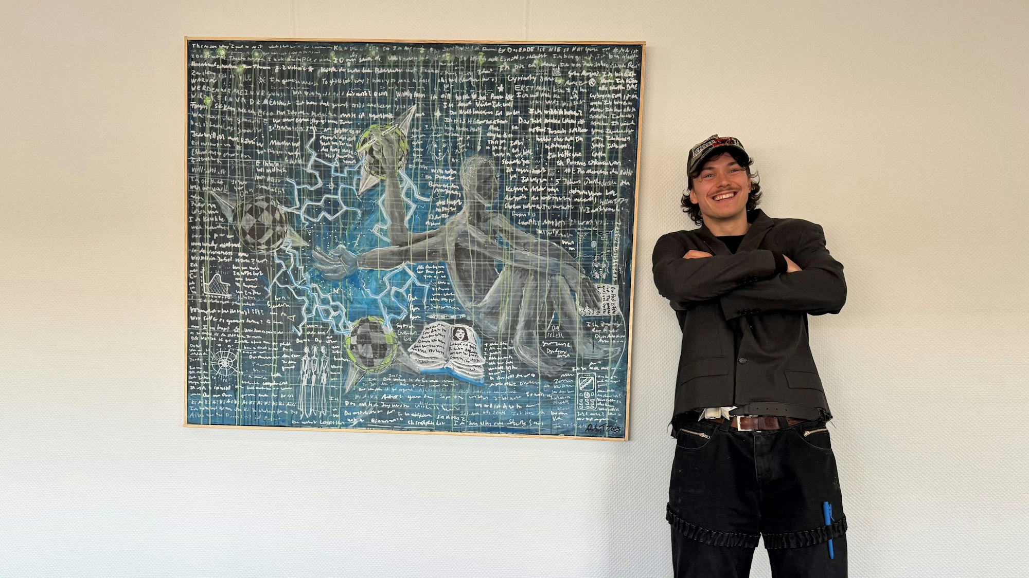 Auf dem Bild ist ein junger Künstler vor einem seiner Werke zu sehen.