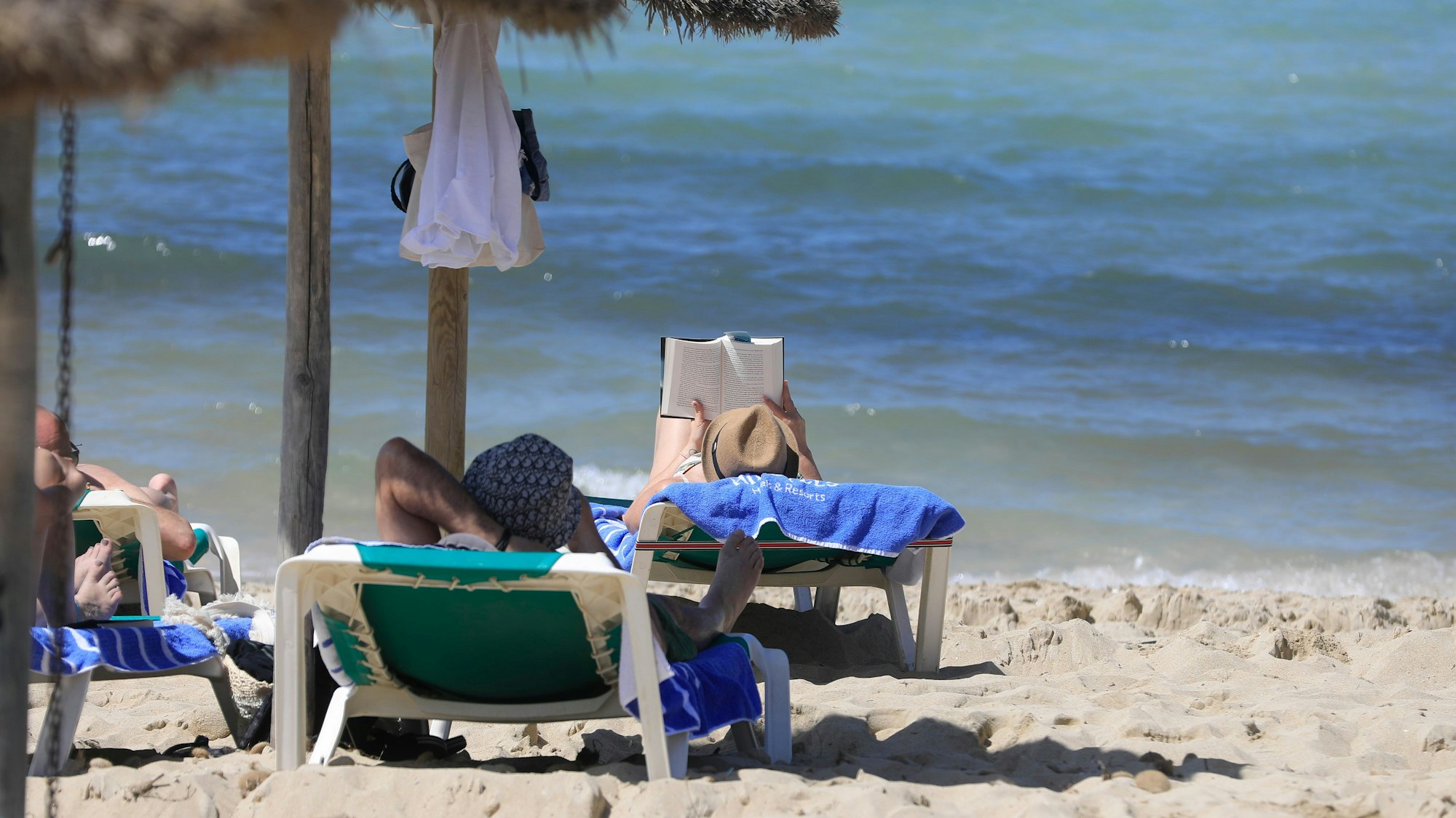 Eine Person liest am Strand Arenal.