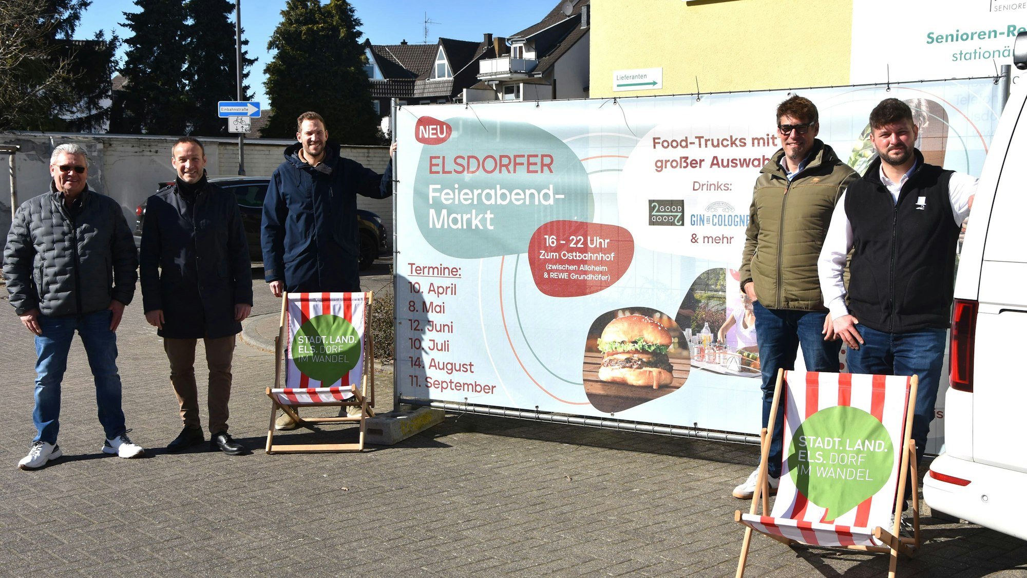 Das Foto zeigt fünf Männer vor einem Plakat des Elsdorfer Feierabendmarkts.