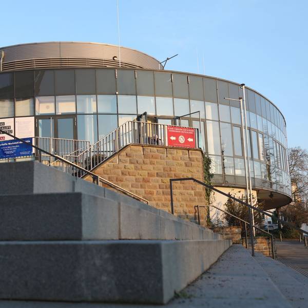 Eine große Treppenanlage und im Hintergrund ein ovales Gebäude mit einer Glasfront.