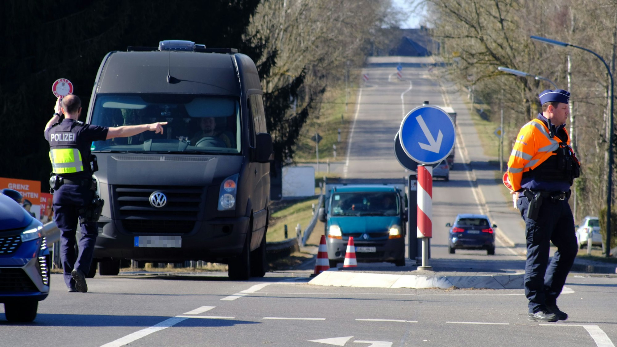 Bei einer gemeinsamen Polizeikontrolle von deutschen und belgischen Kräften winkt ein Polizist einen schwarzen Transporter heraus.