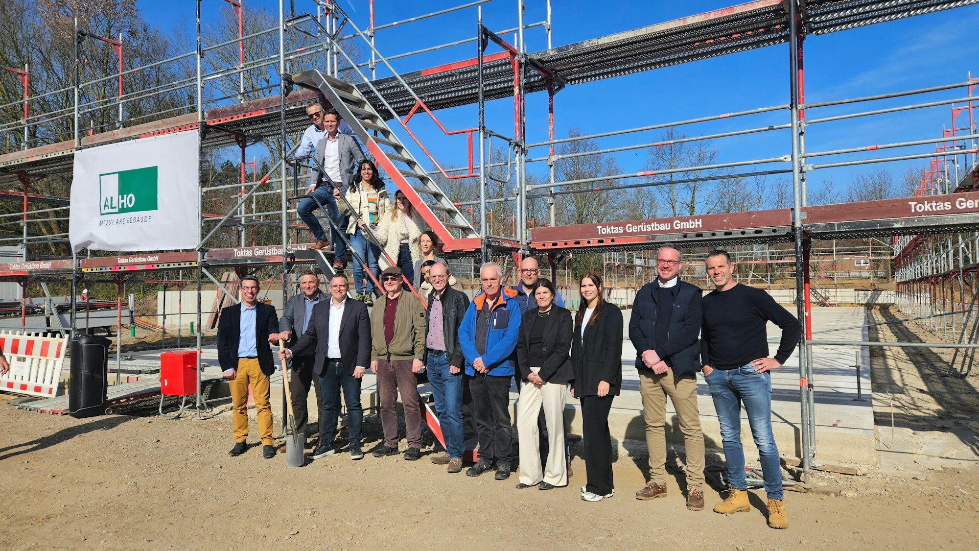 Zu sehen sind zahlreiche Menschen auf einer Baustelle für einen Kindergarten in Bedburg.
