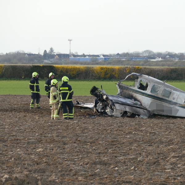 Einsatzkräfte stehen neben einem Flugzeugwrack auf einem Feld in Sankt Augustin.