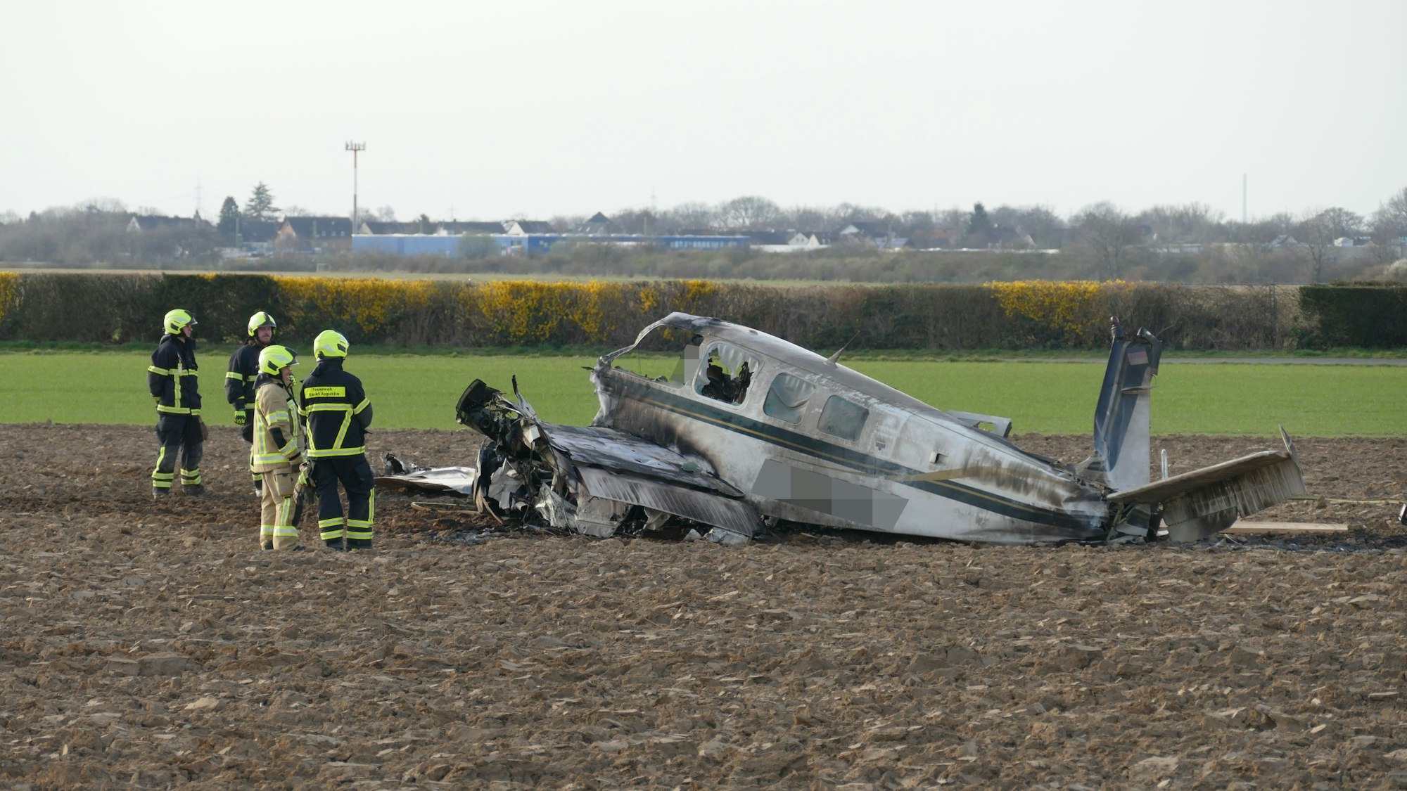 Einsatzkräfte stehen neben einem Flugzeugwrack auf einem Feld in Sankt Augustin.