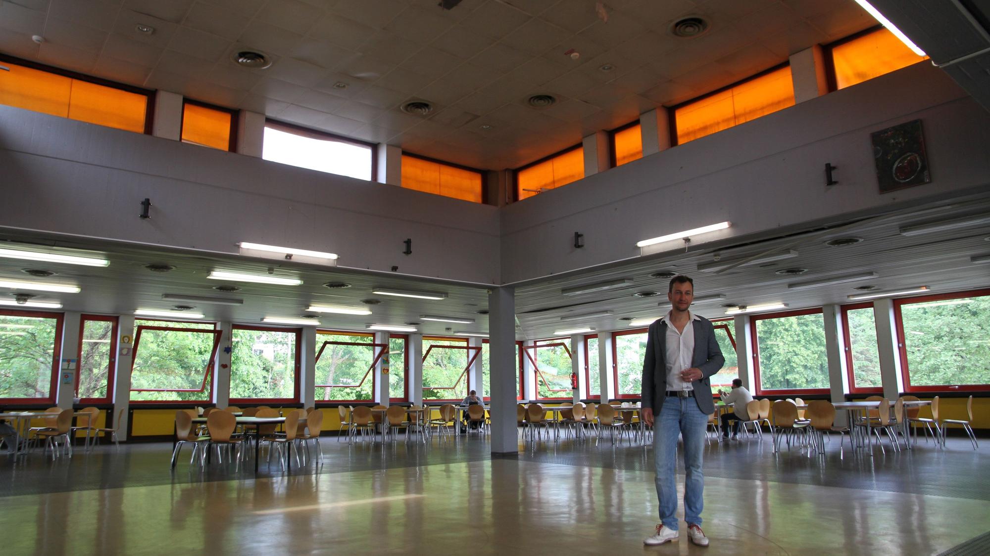 Ein Mann in einem großen Raum mit breiten Fensterbändern.