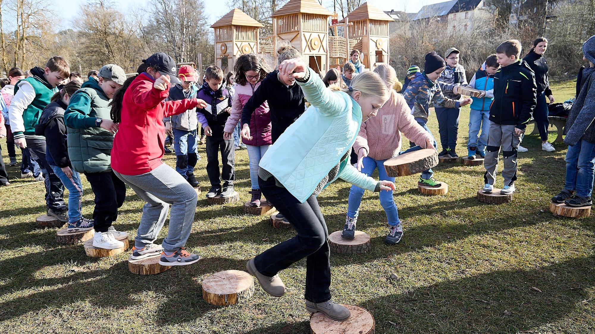 Kinder balancieren auf Holzscheiben, die auf einem Parcours ausgelegt sind. Im Hintergrund ist ein römisches Kastell zu sehen.