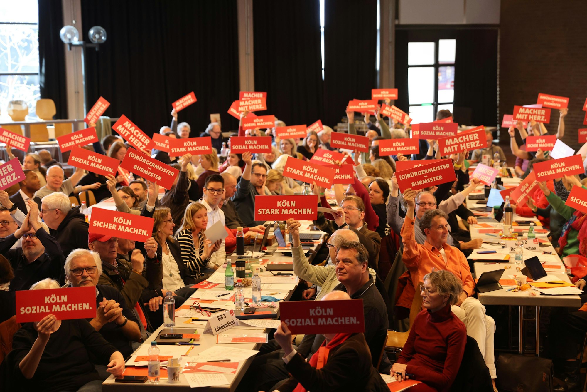 Delegierte der Kölner SPD halten rote Schilder mit politischen Forderungen hoch.