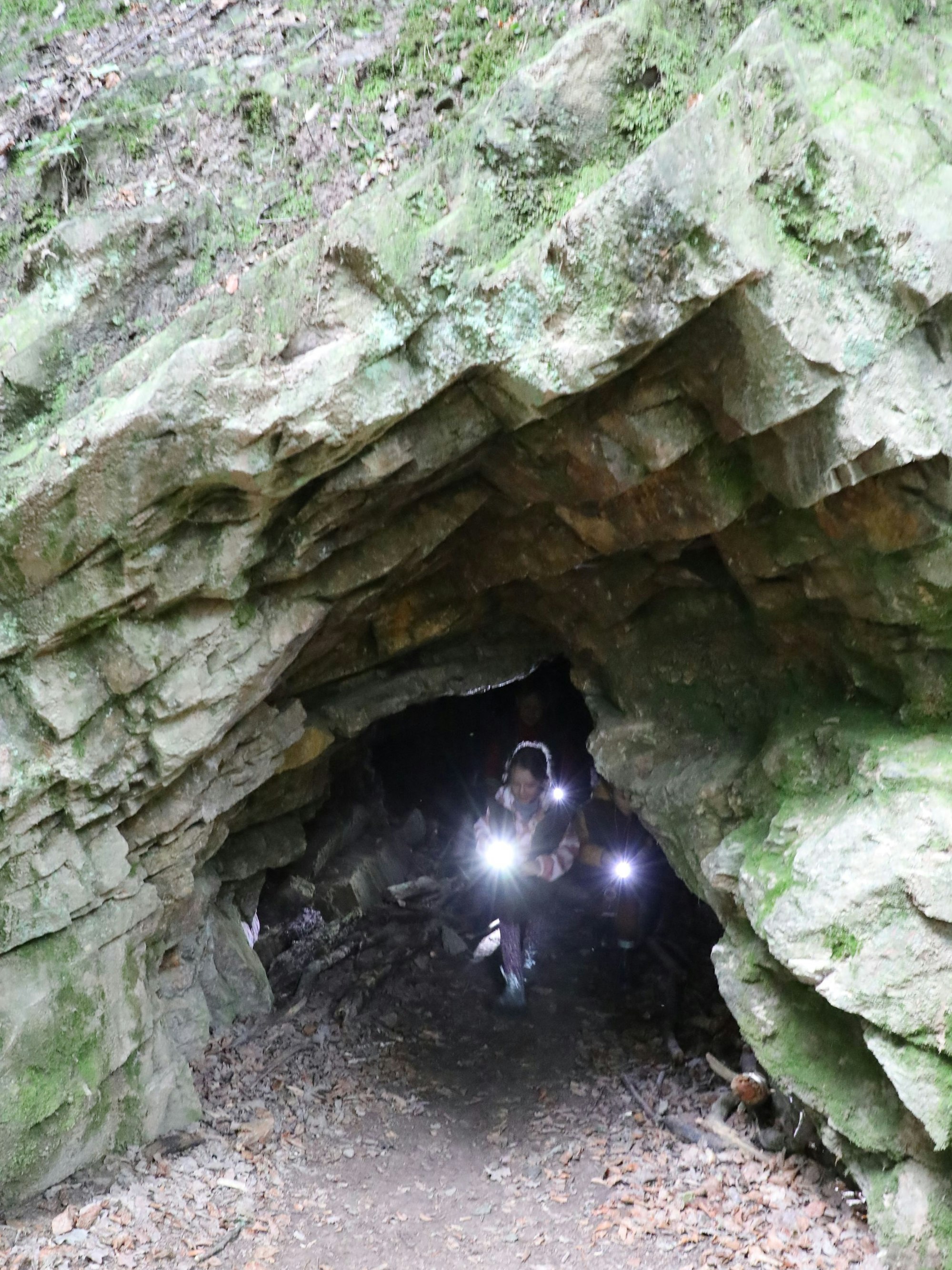 Ein Kind kommt mit einer Taschenlampe aus der Bärenhöhle bei Haus Hardt in Bergisch Gladbach.