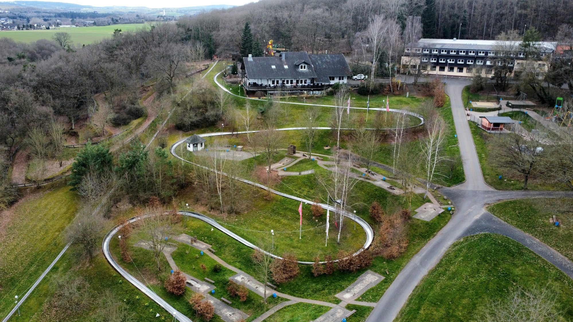 Die Erlebniswelt Eifeltor mit Sommerrodelbahn, Hotel- und Gastronomiegebäuden in Mechernich-Kommern (Drohnenaufnahme).