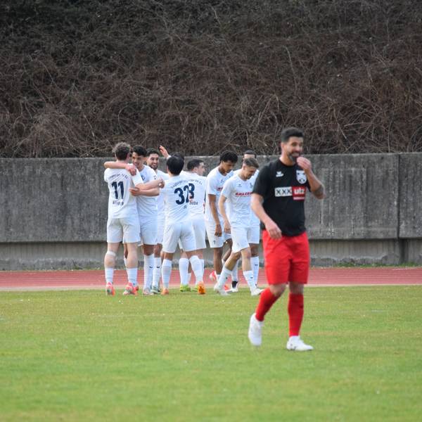 Die Siegburger bejubeln den Führungstreffer, Nils Teixeira vom FC Hennef 05 lächelt nur nach außen hin.
