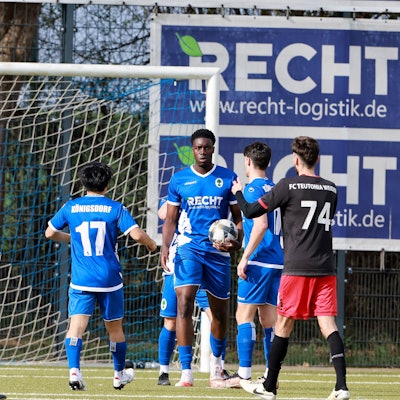 Das Foto zeigt drei in Blau gekleidete Fußballer beim Torjubel