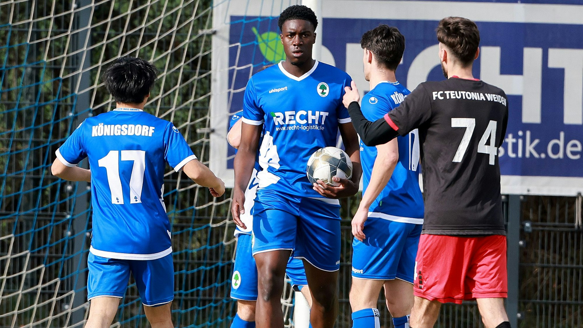 Das Foto zeigt drei in Blau gekleidete Fußballer beim Torjubel