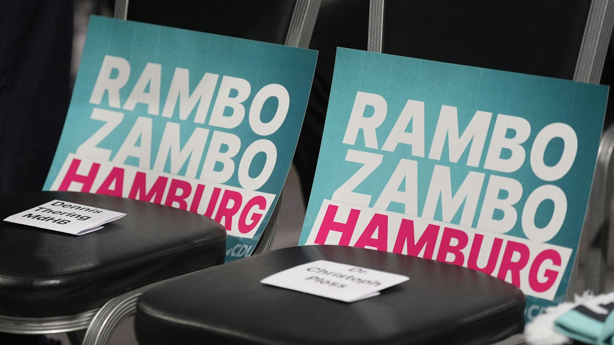 28.02.2025, Hamburg: Plakate mit der Aufschrift «Rambo Zambo» liegen auf Stühlen vor der Bühne im Cruise Center Baakenhöft während des CDU-Wahlkampfabschlusses vor der Bürgerschaftswahl. Am Sonntag wird in Hamburg eine neue Bürgerschaft gewählt. Foto: Marcus Brandt/dpa +++ dpa-Bildfunk +++