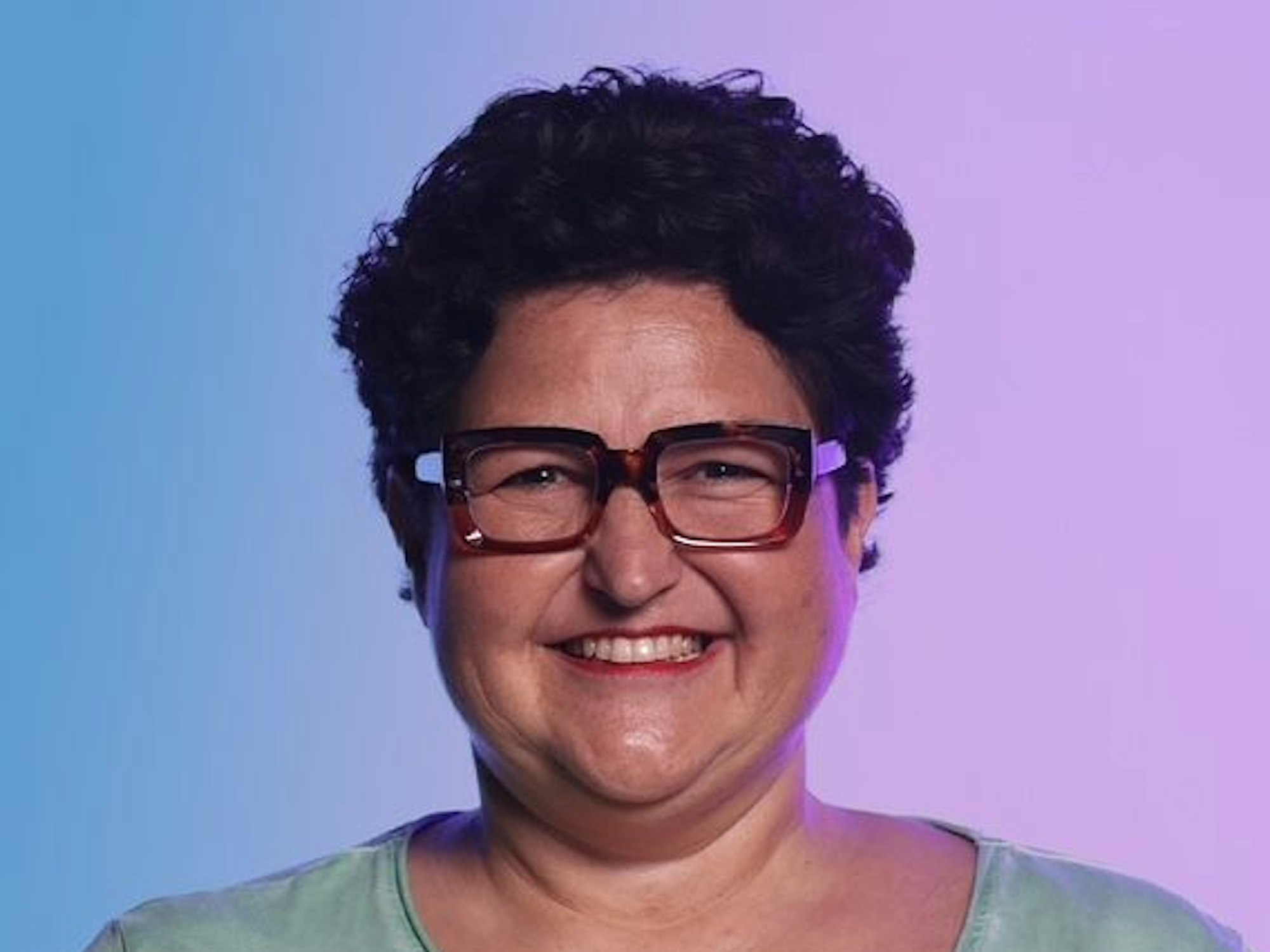 Porträtbild einer Frau mit kurzem schwarzen Haar und Brille.