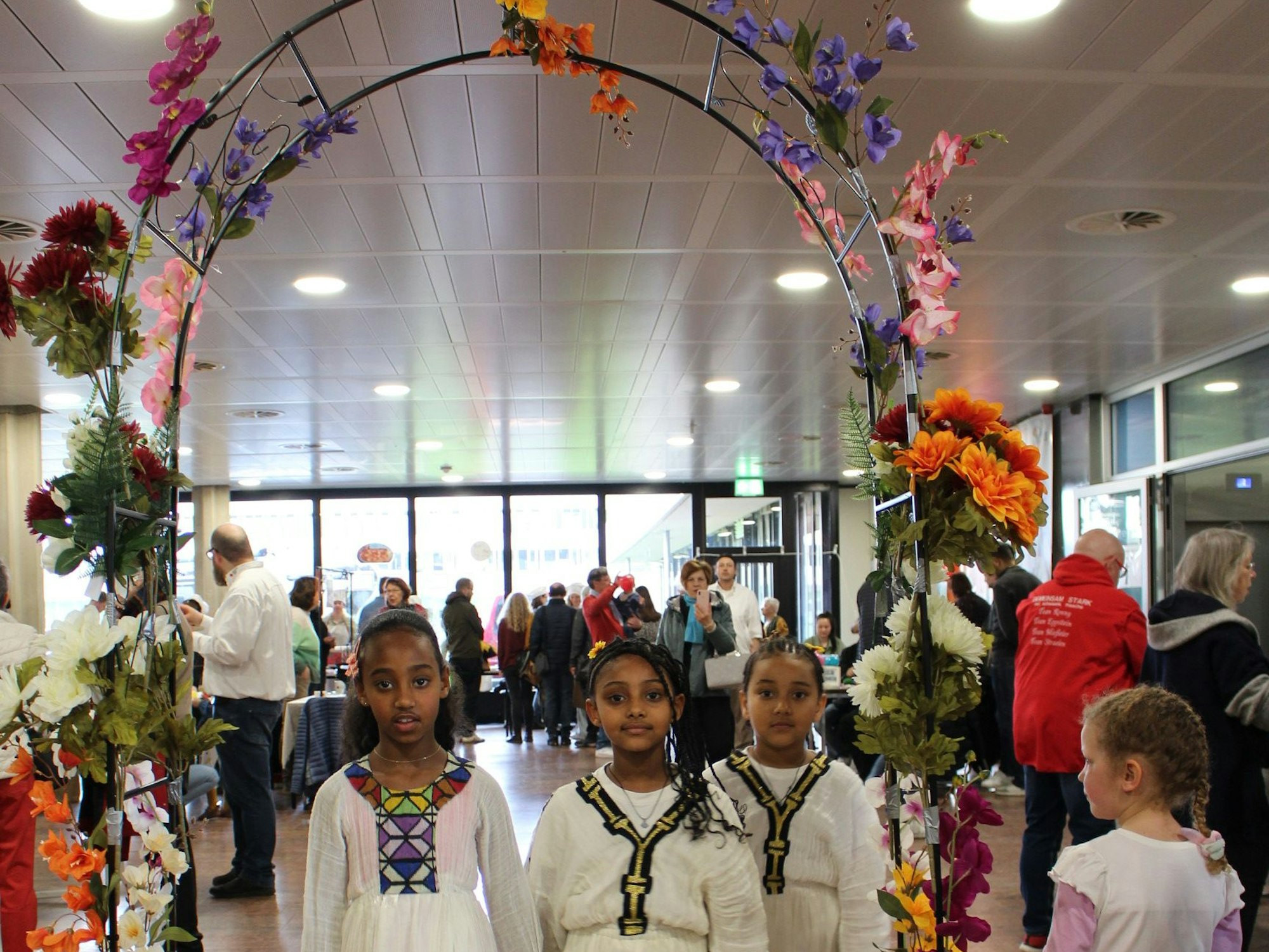 Kinder gehen durch einen geschmückten Garten-Torbogen.