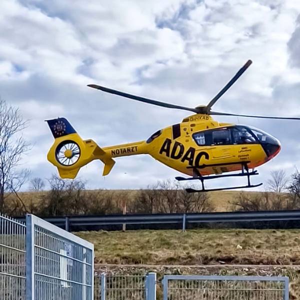 Ein Rettungshubschrauber setzt neben einem Sportplatz zur Landung an.