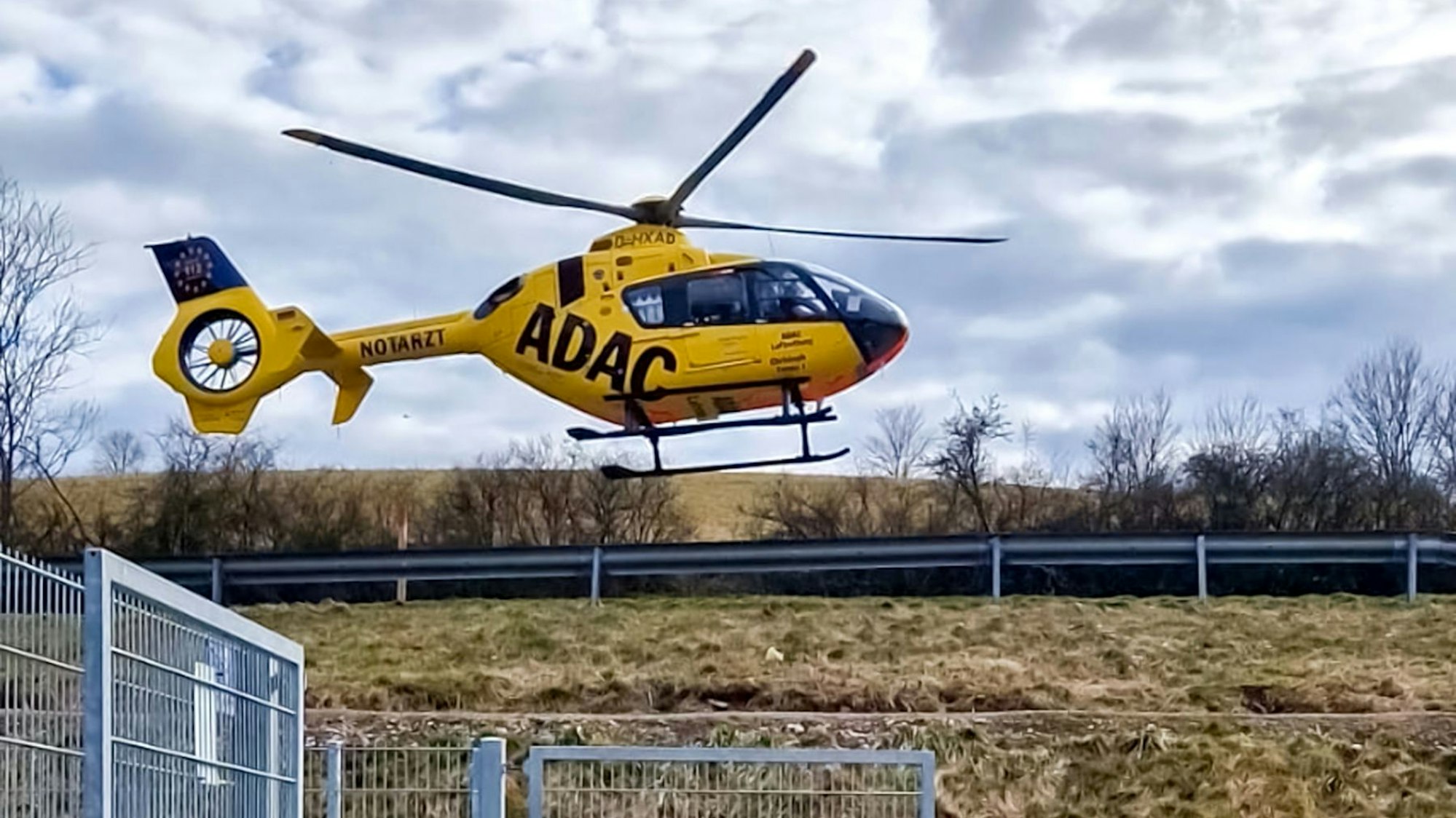 Ein Rettungshubschrauber setzt neben einem Sportplatz zur Landung an.
