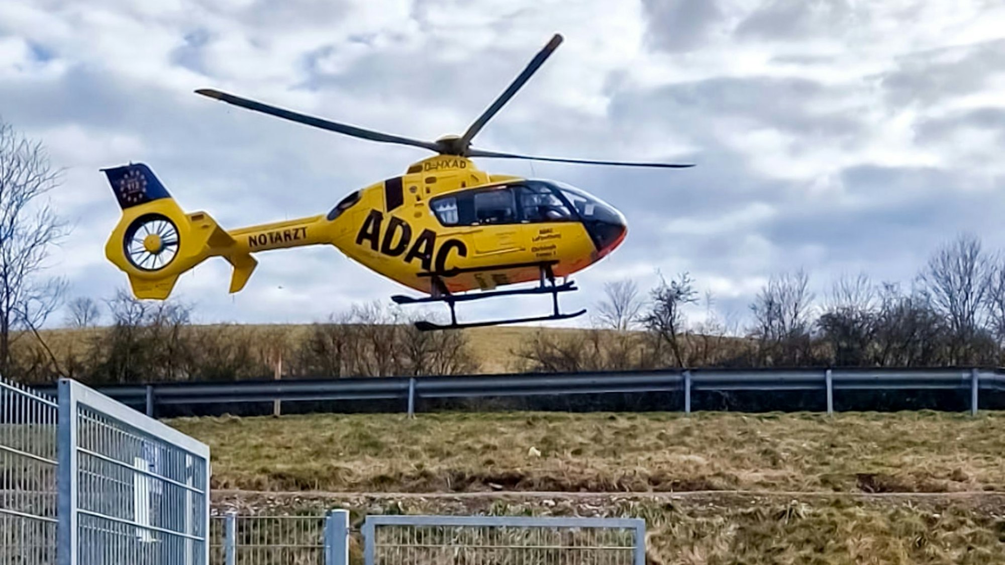 Ein Rettungshubschrauber setzt neben einem Sportplatz zur Landung an.