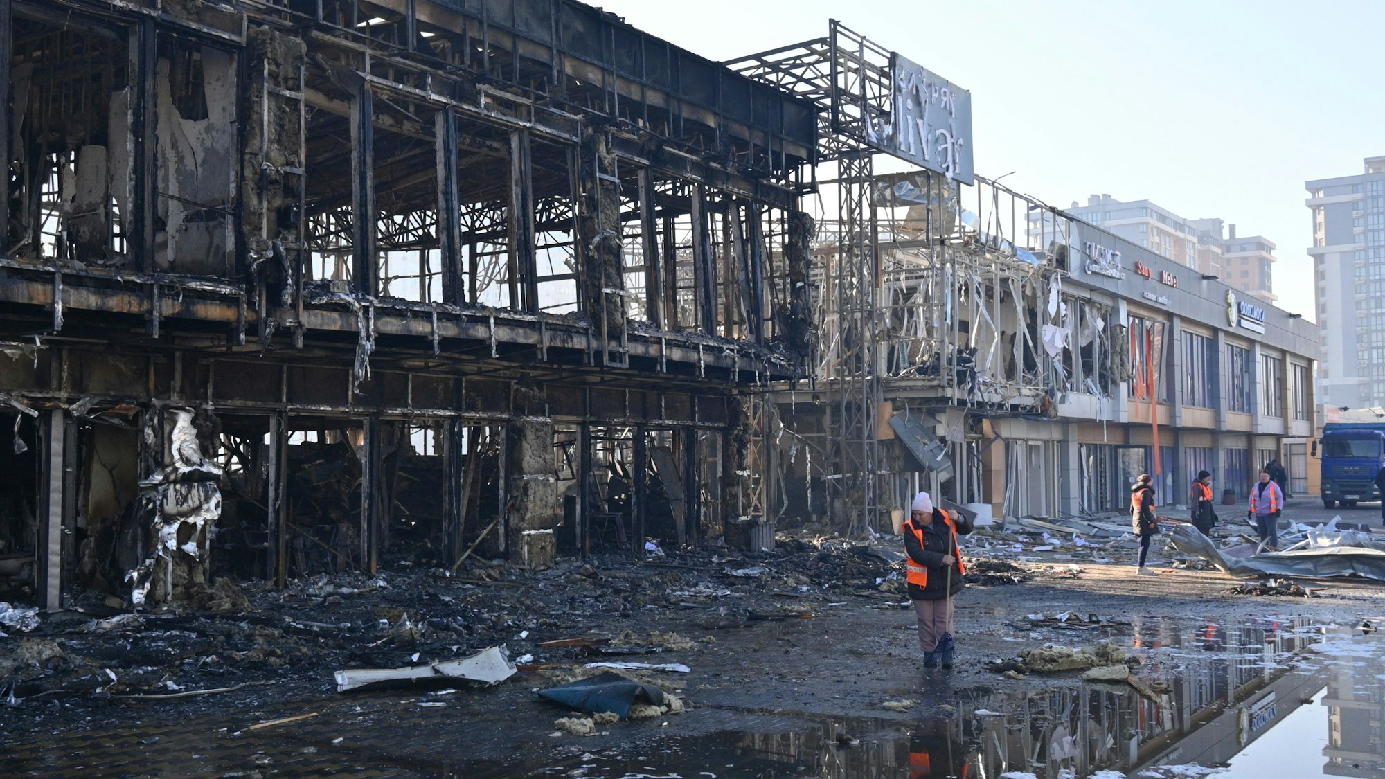 21.03.2025, Ukraine, Odessa: Städtische Arbeiter räumen auf, nachdem russische Drohnen während des nächtlichen Angriffs Geschäfte getroffen haben.