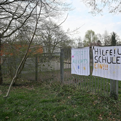 Auf dem Plakat steht: Hilfe! Unsere Schule stürzt ein.