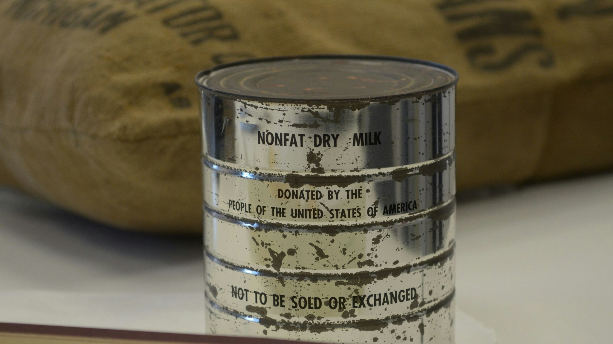 Das Foto zeigt eine Dose mit starken Altersspuren. Die Aufschrift am oberen Rand lautet „Nonfat Dry Milk“.
