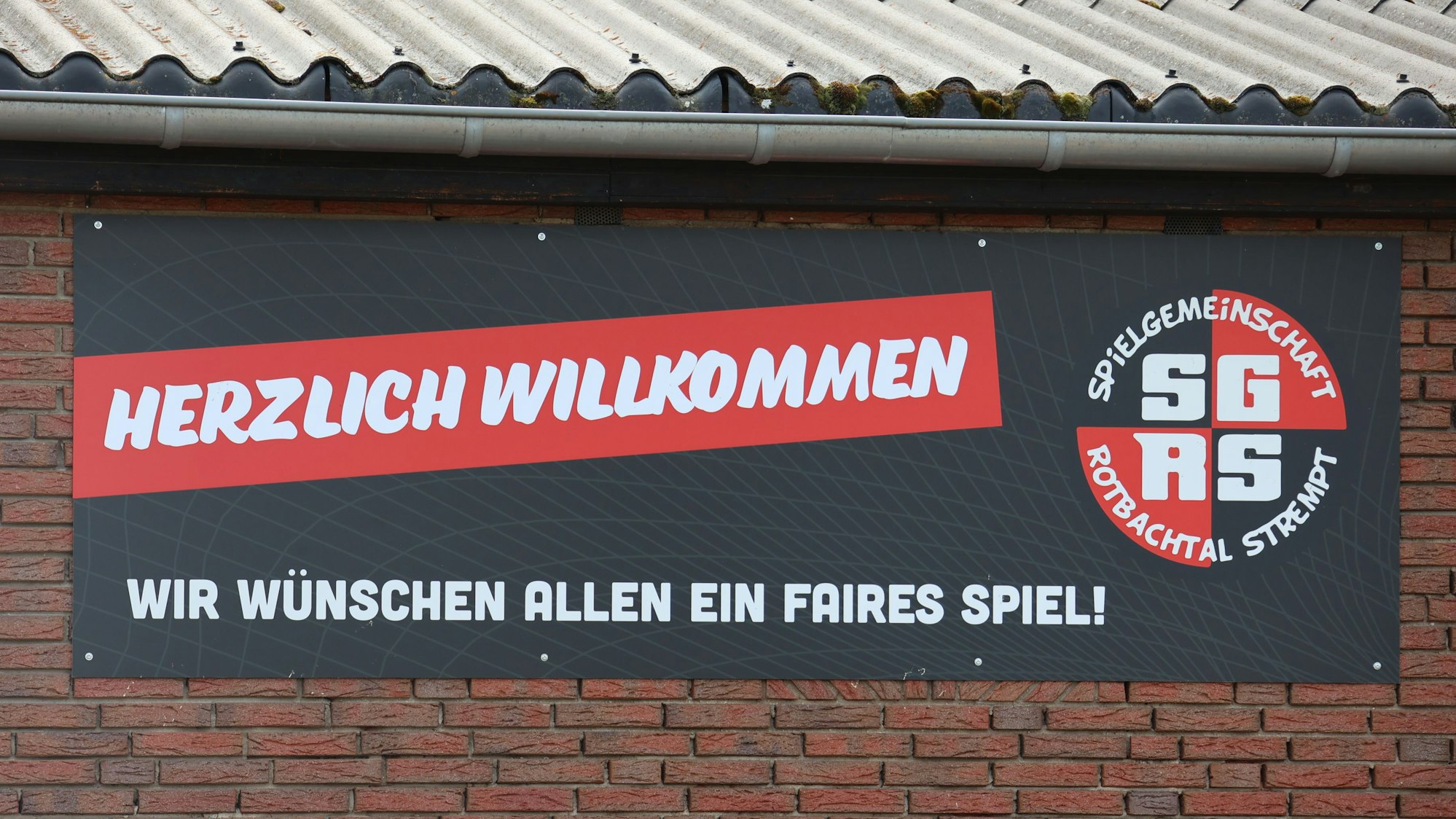 Auf einem Schild am Sportplatz der SG Rotbachtal/Strempt steht „Herzlich willkommen, wir wünschen allen ein faires Spiel!“
