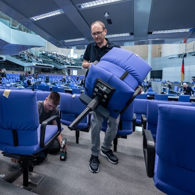 Handwerker bauen den Plenarsaal im Deutschen Bundestag für die konstituierende Sitzung des 21. Deutschen Bundestag und die neue Legislaturperiode um.