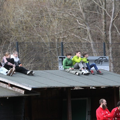 Sechs Kinder sitzen auf dem Dach und verfolgen ein Fußballspiel.